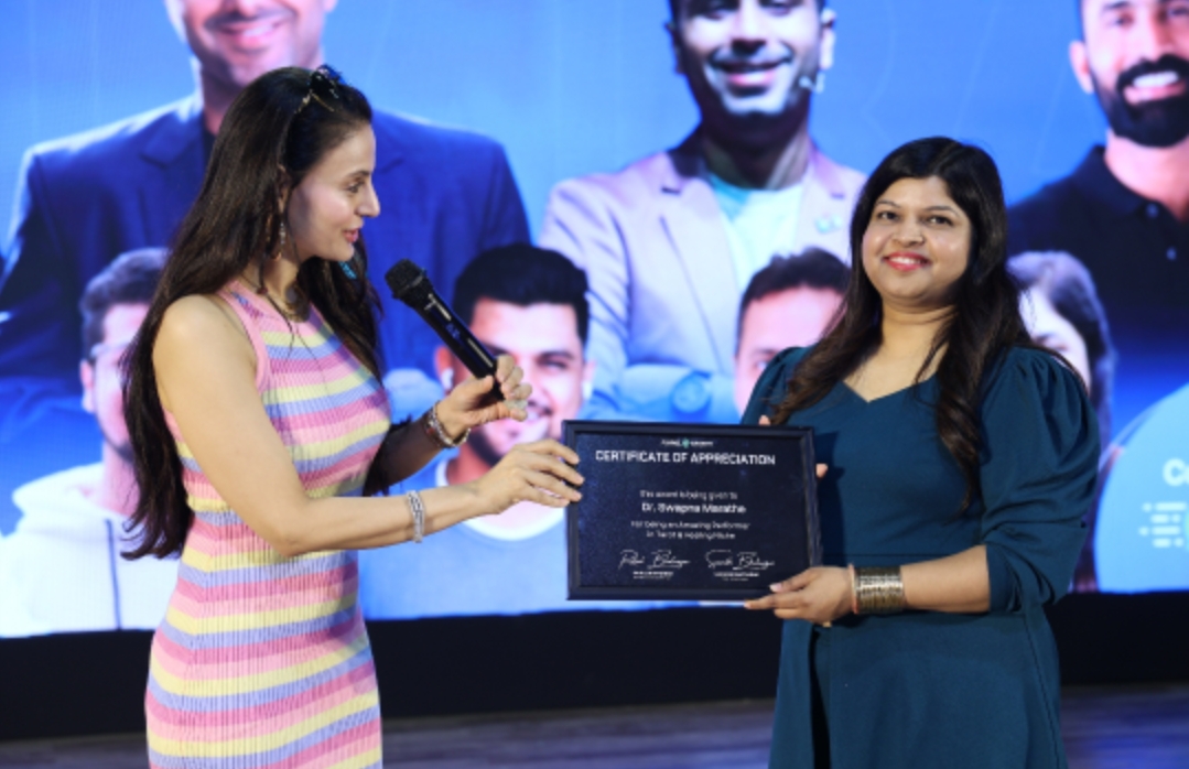 Dr. Swapna Marathe receiving a Certificate of Appreciation on stage